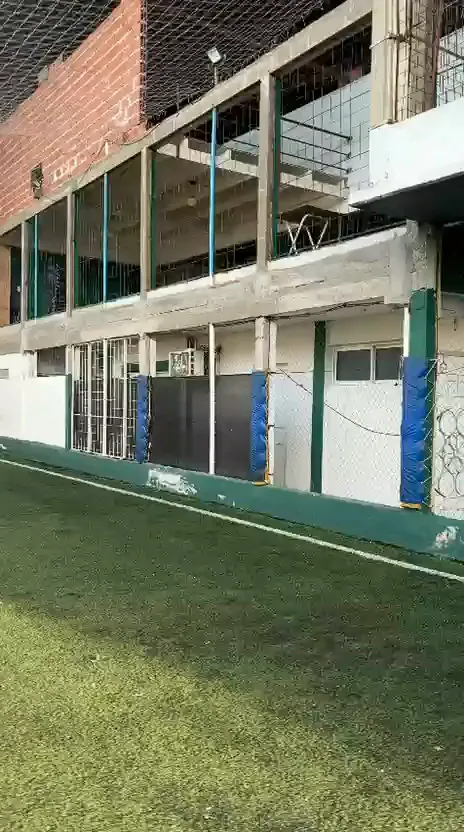 Lateral de la cancha con el frente del edificio y el balcón del primer piso