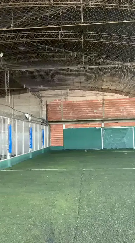 Cancha con red cenital, muro de ladrillo y arco al fondo