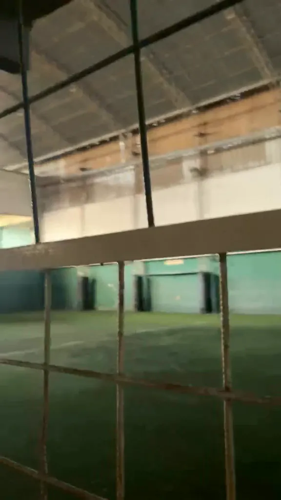 Cancha cubierta vista a través de la reja del pasillo