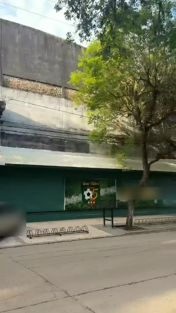 Fachada verde del complejo con el mural de Reco Fútbol 5 y bicicletero en la vereda