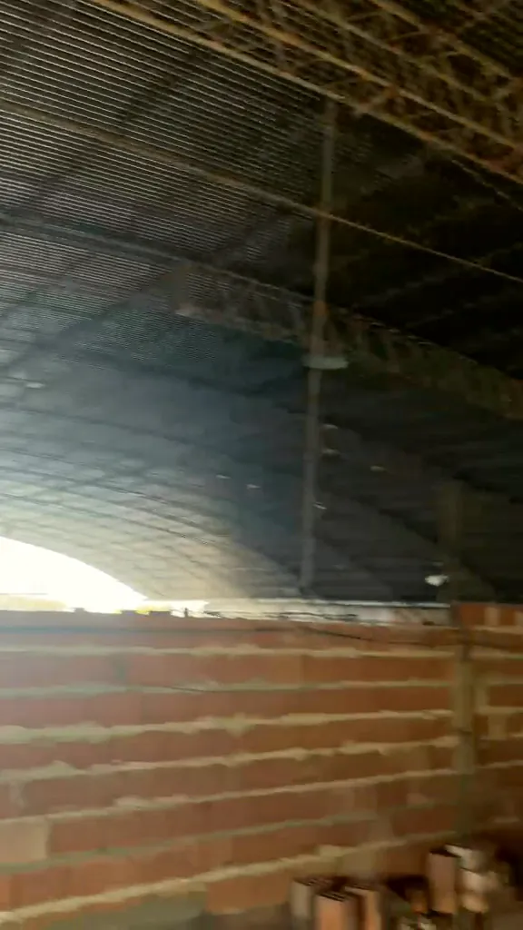 Gran nave con techo parabólico de estructura metálica y muros de ladrillo en construcción