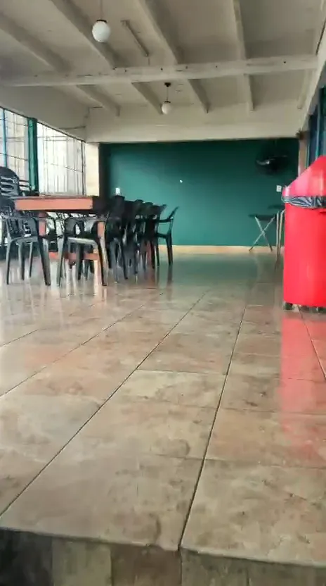 Salón superior con mesas y sillas, piso cerámico y pared verde