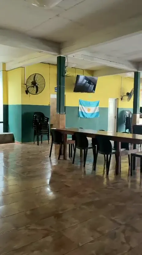 Salón con columna verde, pantalla de TV y bandera argentina en la pared